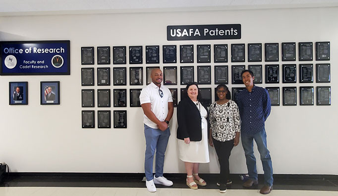 USPTO staff from the Rocky Mountain Regional Office posing in front of U.S. Air Force Academy (USAFA) patent plaques on a wall