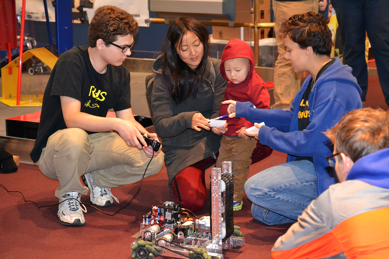 A student demonstrates a FIRST robot to onlookers