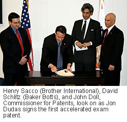 Henry Sacco (Brother International), David Schlitz (Baker Botts), and John Doll, Commissioner for Patents, look on as Jon Dudas signs the first accelerated exam patent. 