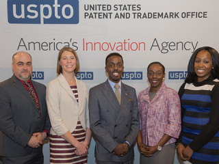 Five members of the USPTO and MBDA pose in front of a media backdrop.