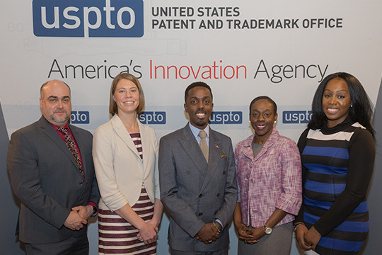 Five members of the USPTO and MBDA pose in front of a media backdrop.