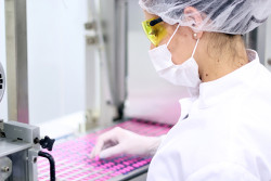 一位科学家戴着口罩、发网和护目镜在实验室进行实验的特写镜头