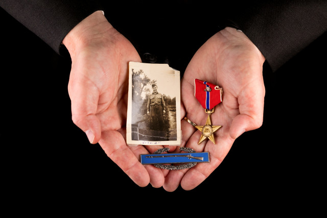 hands holding A Bronze Star, Combat Infantryman Badge, and 1945 portrait from Germany of Dean’s grandfather, Herman Robichaux Sr., who served under General George S. Patton during the Battle of the Bulge. 