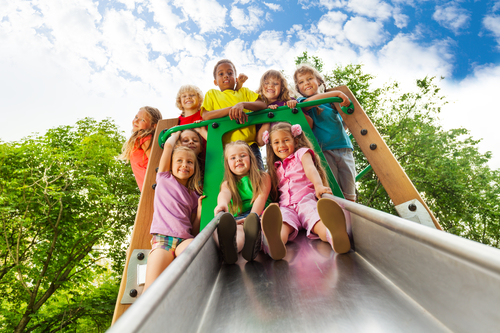 Photo of a group of children about to go down a playground slide.
