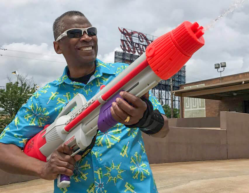 Image: Johnson plays around with a Super Soaker® while wearing a shirt patterned with images of his famous creation.