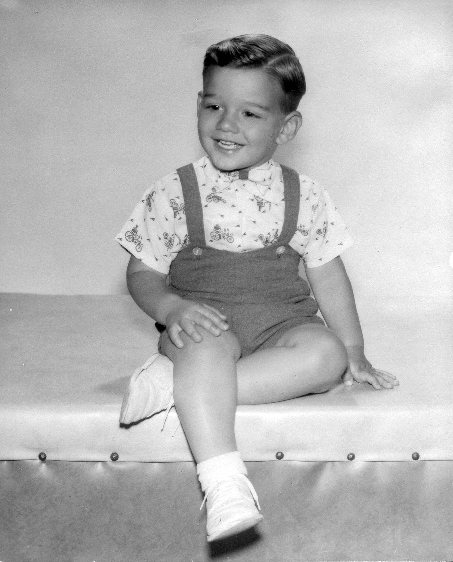 Age three Marty Rothblatt in 1957, wearing suspenders, happy posed in photo studio, black and white.