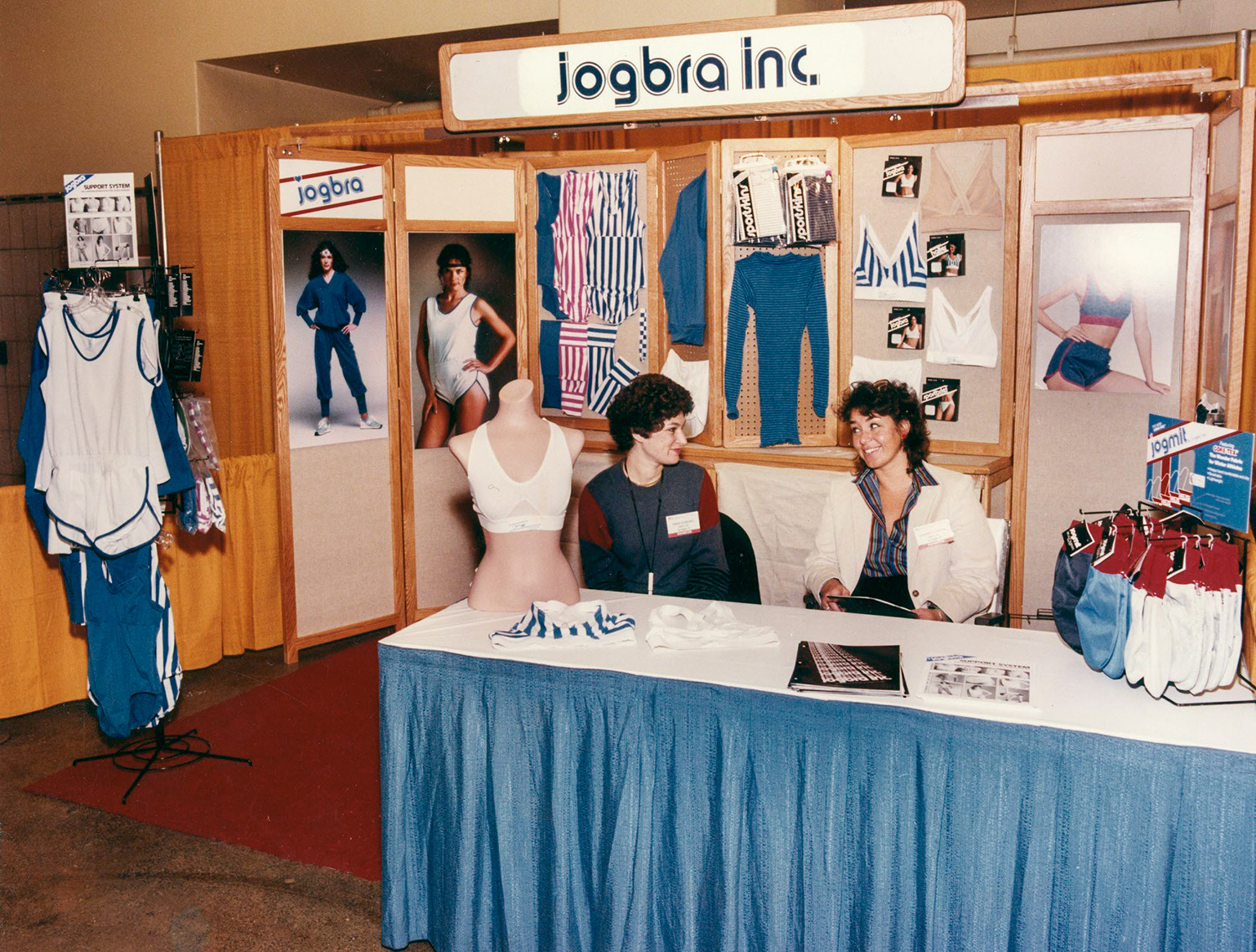 Hinda Miller and Lisa Lindahl sit at a booth surrounded by their merchandise.