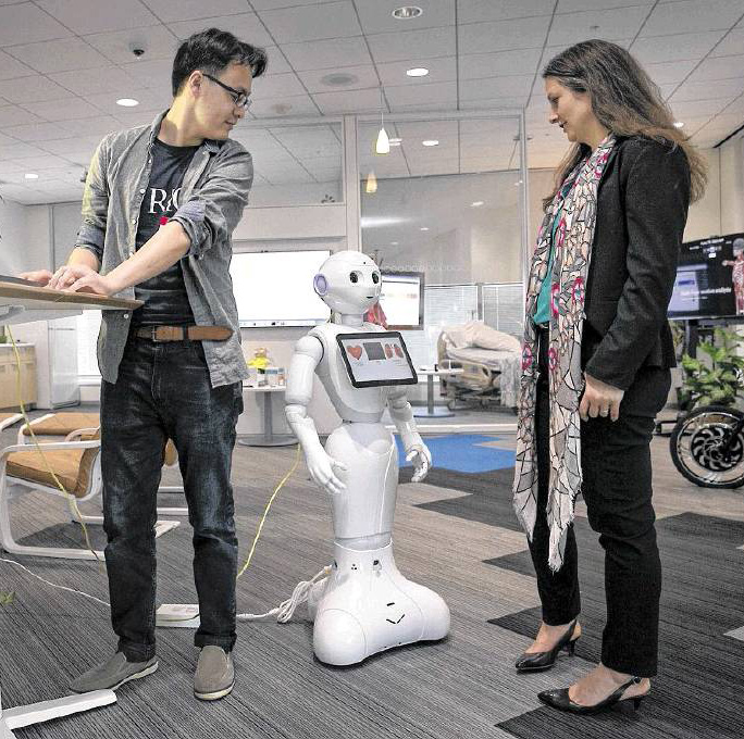 Susann Keohane and co-worker at the IBM aging in place environment/lab with the friendly looking Multi-Purpose Eldercare Robot Assistant (IBM MERA), a first of a kind Watson-enabled application designed to aid the elderly and assist caregivers with real-time information about their health.