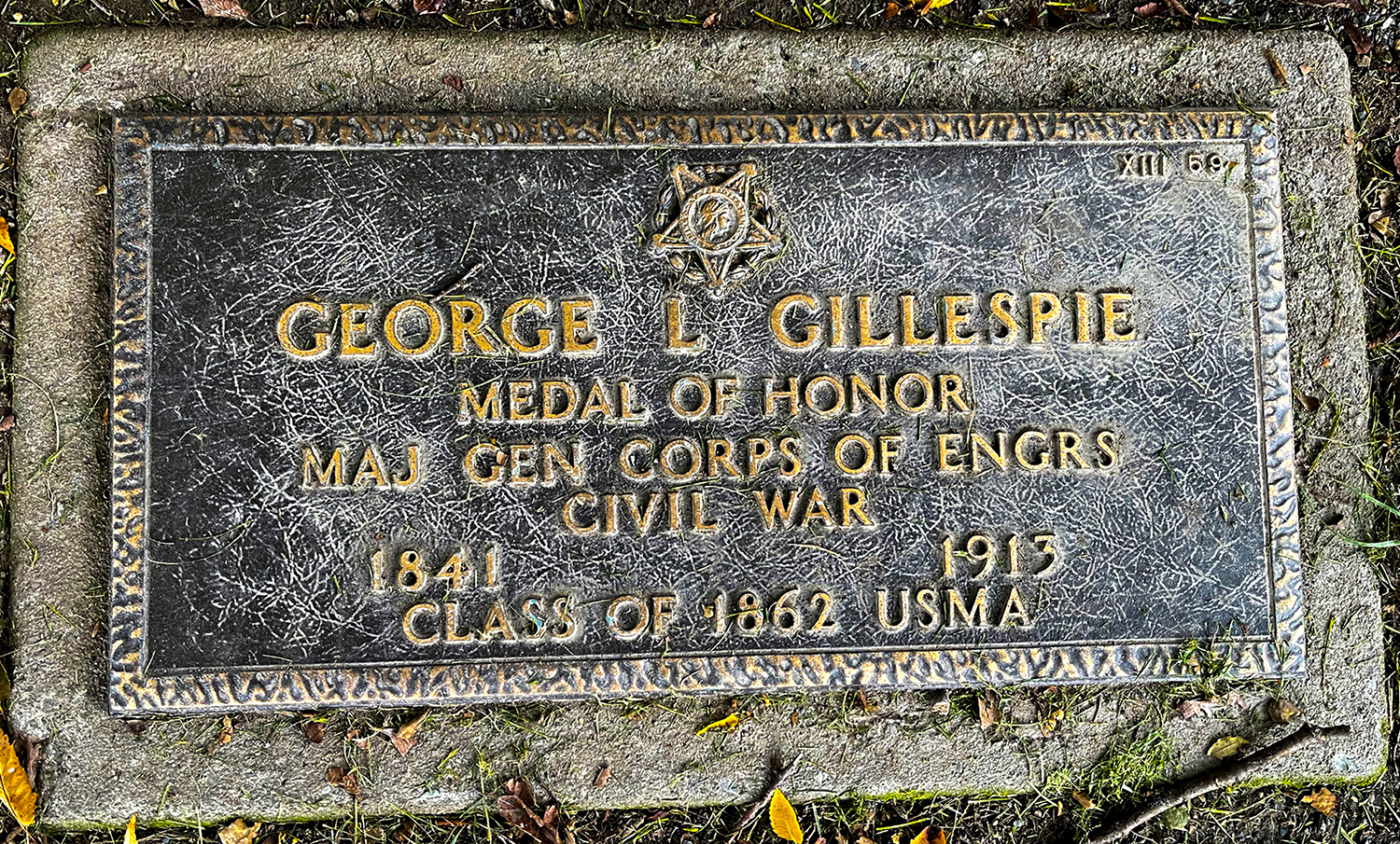 A simple, ground-level grave marker for George L. Gillespie, engraved on which is the five-pointed star design of the Medal of Honor.