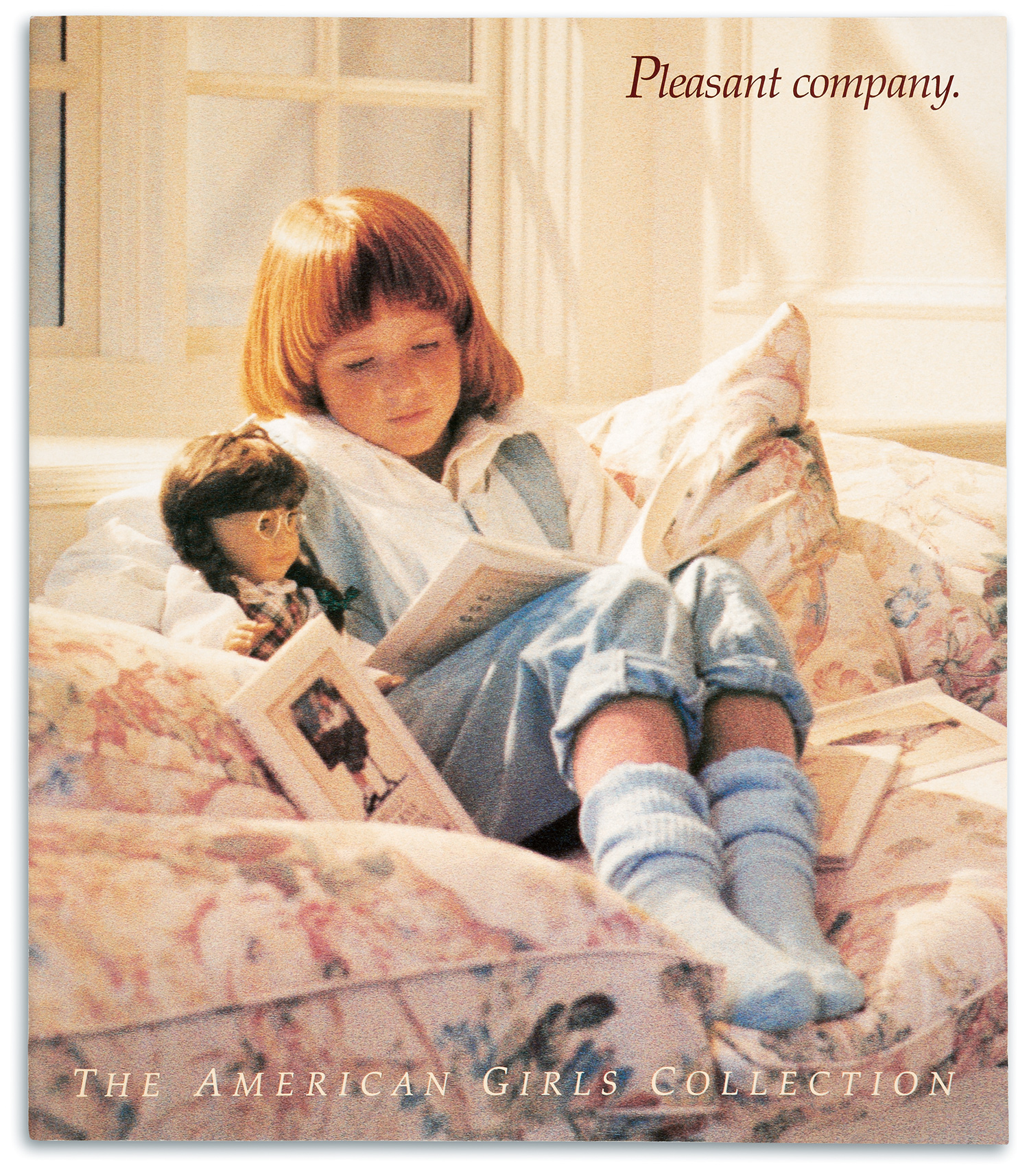 The cover of the first catalog of the Pleasant Company produced in 1986.Bathed in sunshine, a young girl with a bowl-cut wearing a jeans jumper and socks, cozily curls up on a pillowy, pastel-floral window seat and reads to her doll from a book in her lap. Several additional books whose covers match the doll by her side are strewn about.