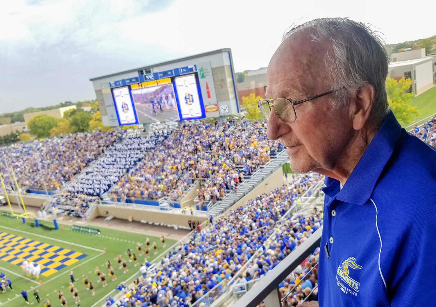 Al Kurtenbach watching game in front of a Daktronics display at South Dakota State University's football stadium. Photo by David Kadas/USPTO.