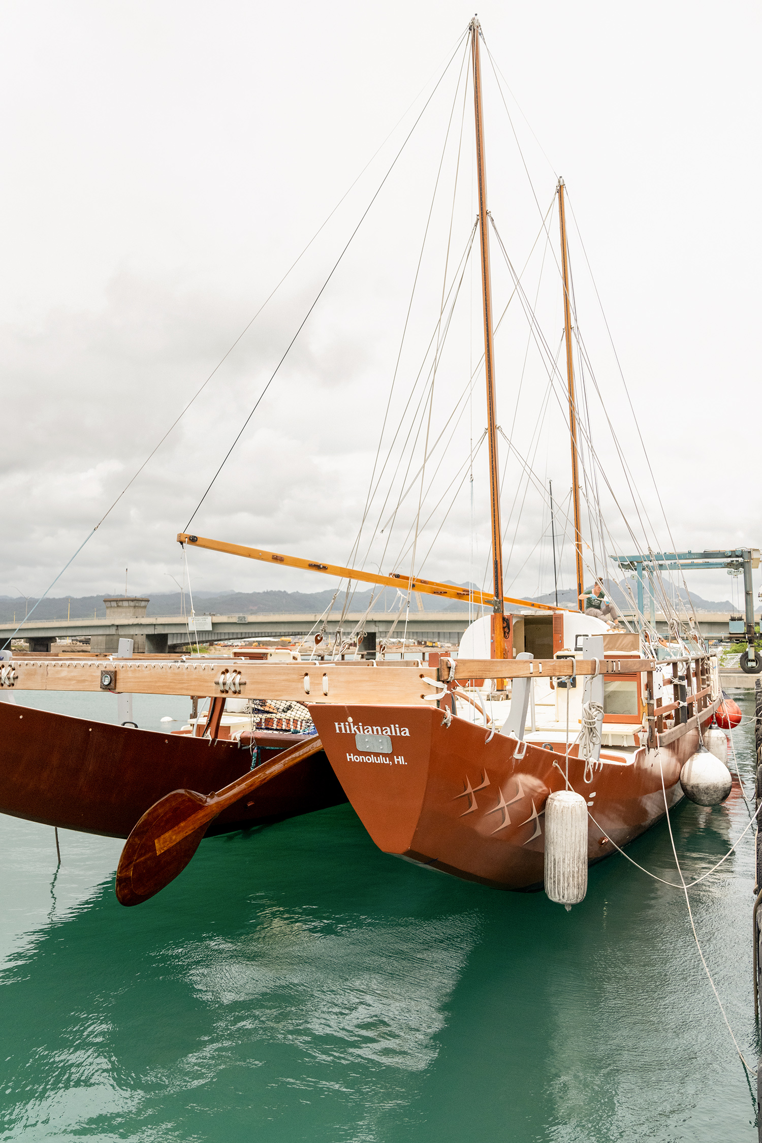 Photograph shows the front of a traditional Polynesian sailing canoe in wet dock in Hawaii. 
