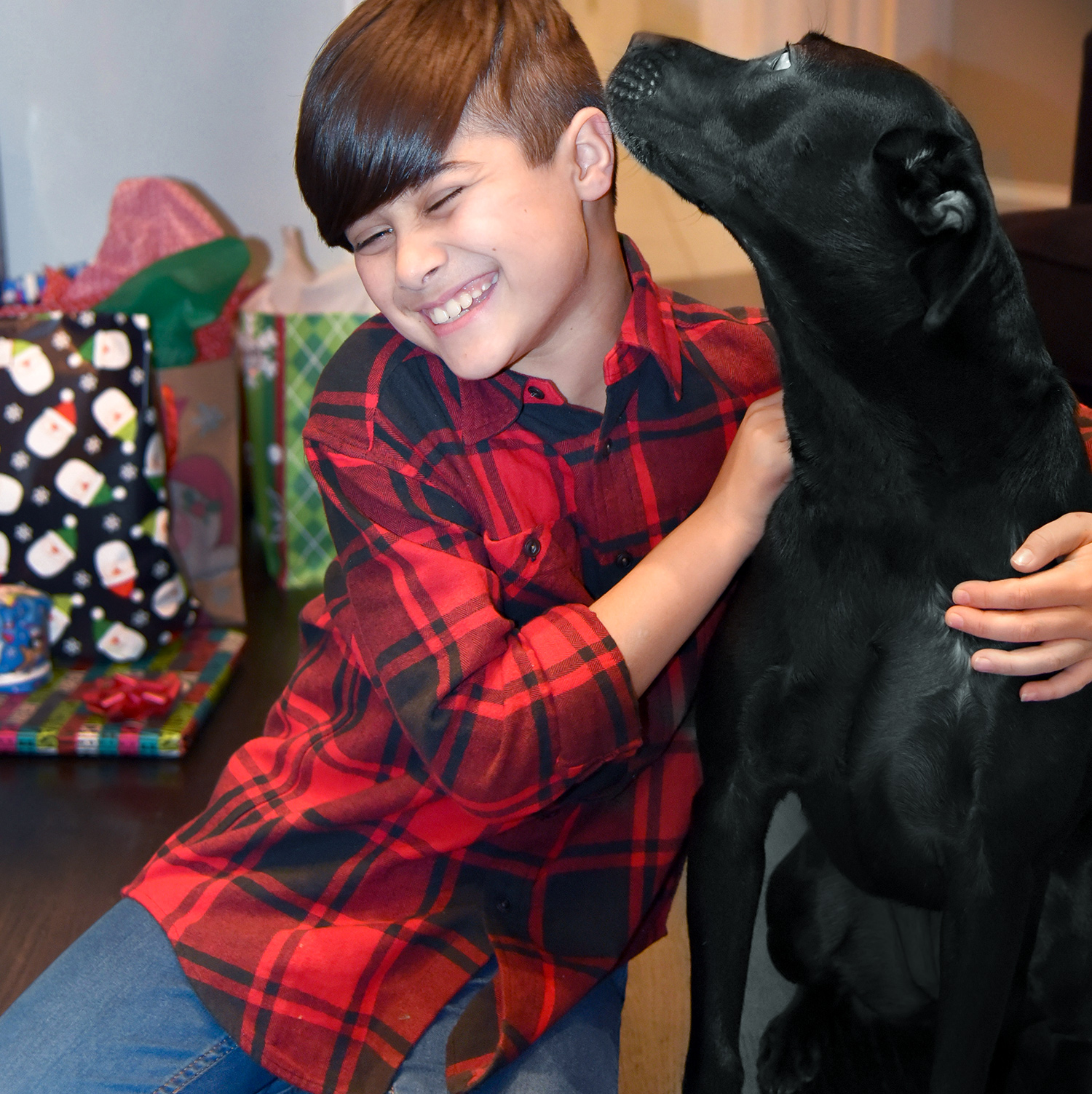 A young teenage boy hugs dog next to him