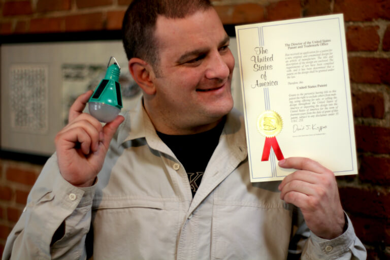 Image: Steve Katsaros holding patent document and Nokero solar light