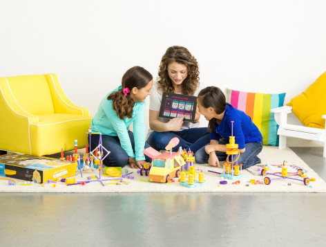 Debbie Sterling and two girls play with GoldieBlox on the floor.
