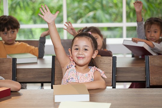Girl in classroom raising hand