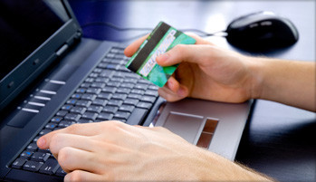 Man holding credit card above laptop keyboard