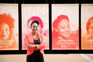 Arlyne Simon stands in front of a display with her photo under the word "innovation."
