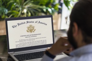 Silhouette of a man looking at a computer screen showing the U.S. Trademark Certificate of Registration