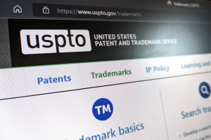 Close up image of the USPTO.gov website showing the logo and navigation button to trademark basics information.