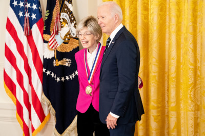 Mary-Dell Chilton wearing a pink blazer and dark pants poses for a picture with President Biden after receiving the National Medal of Technology and Innovation.