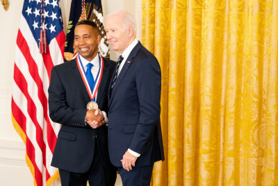 Juan Gilbert wearing a dark suit shakes President Biden’s hand, right after receiving the National Medal of Technology and Innovation.