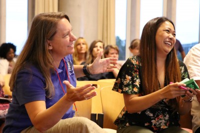 Two women laughing and engaging with an offscreen speaker