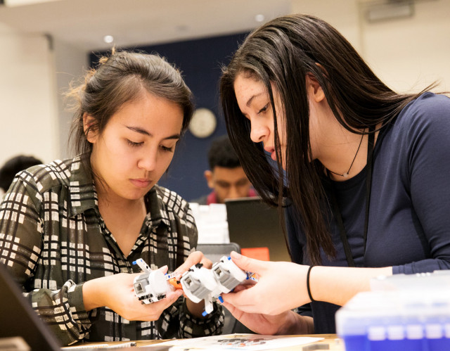 Two high school students assembling a robot.