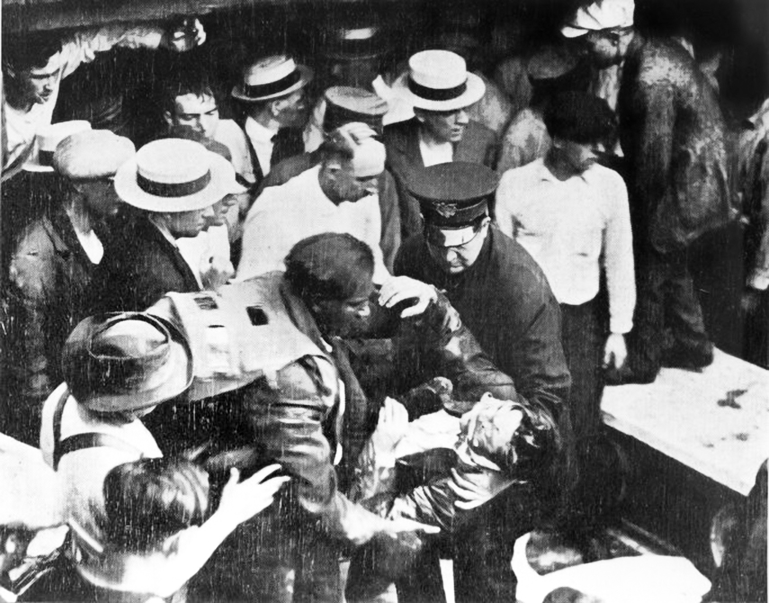 Morgan, with his safety hood draping across his back, supports an unconscious man while a crowd gathers around him